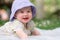 adorable and happy baby girl in summer hat embraces the joys of playfulness on a soft blanket. Laughing as she explores the