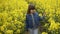 Adorable and happy little girl walking through blooming, yellow canola field at sunny summer day