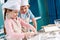 adorable happy little kids in chef hats and aprons making dough together