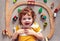 Adorable happy redhead baby boy laying on the carpet among railway tracks and trains, wooden toys