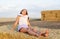 Adorable happy smiling ittle girl child sitting on a hay rolls in a wheat field