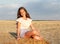 Adorable happy smiling ittle girl child sitting on a hay rolls in a wheat field