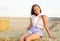 Adorable happy smiling ittle girl child sitting on a hay rolls in a wheat field