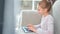 Adorable happy teen girl chatting typing on keyboard using laptop pc sitting sofa