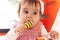 Adorable hispanic baby bitting maraca sitting on bed at bedroom