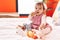 Adorable hispanic baby bitting maraca sitting on bed at bedroom