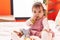 Adorable hispanic baby bitting maraca sitting on bed at bedroom