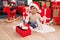 Adorable hispanic boy unpacking robot toy sitting on floor by christmas tree at home