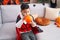 Adorable hispanic boy wearing halloween costume inflating balloon at home