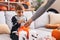 Adorable hispanic boy wearing skeleton costume receiving sweets on pumpkin basket at home