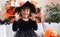 Adorable hispanic girl having halloween party doing scare gesture at home