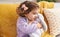 Adorable hispanic girl hugging rabbit toy sitting on sofa at home