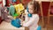 Adorable hispanic girl playing with telephone toy standing at kindergarten