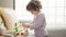 Adorable hispanic girl playing with toy standing at home