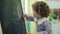 Adorable hispanic girl preschool student drawing on blackboard at kindergarten