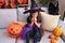 Adorable hispanic girl wearing witch costume inflating balloon at home