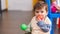 Adorable hispanic toddler sucking ball sitting on floor at kindergarten