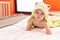 Adorable hispanic toddler wearing funny towel lying on bed at bedroom