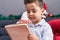 Adorable hispanic toddler writing letter to santa claus sitting on sofa by christmas decoration at home