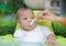 Adorable infant baby boy sitting in the chair and eating food for the first time. Hand of mother feeding food into baby mouth by