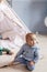 Adorable infant boy playing with toy tent in cozy blue playroom