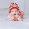 adorable infant child in red and white striped hat with pompom playing with toy angel