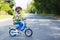 Adorable kid boy in red helmet and colorful raincoat riding his