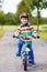 Adorable kid boy in red helmet and colorful raincoat riding his