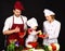 Adorable kid in chef hat with her parents. Mother and father teaching boy how to cook. Concept of friendly family  mutual