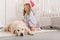 adorable kid with curly hair pretending veterinarian and examining golden retriever