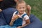 Adorable kid girl holding ice cream in hands, sitting next to fathe on farameless chair outdoor, father and his little doughter