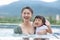 Adorable kid girl smiling her mother with love and happiness feeling in swimming pool.Asian young mother smile with her sweet