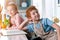 adorable kids in aprons smiling at camera while cooking with cookbook