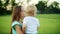 Adorable kids standing in green field. Elder sister holding brother on hands