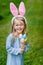 Adorable laughing little girl with pink bunny ears and holding bunch of painted colour eggs