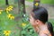 Adorable little Asian child girl explorer beautiful blossom yellow flowers in summer garden. Close-up nature as researcher