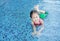 Adorable little Asian child girl wear mermaid swimming suit has fun at the pool