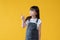An adorable little Asian girl in a cute jeans dress is looking and pointing her finger aside