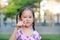 Adorable little Asian girl in garden with pointing at camera. Portrait smiling kid in park. Focus at child face
