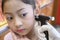Adorable little Asian girl having ear piercing process.