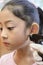 Adorable little Asian girl having ear piercing process.