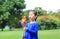 Adorable little Asian kid girl blowing wind turbine in the summer garden