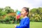 Adorable little Asian kid girl blowing wind turbine in the summer garden