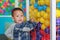 Adorable little baby boy playing colorful plastic ball in cage with looking camera