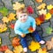 Adorable little baby girl in autumn park on sunny warm october day with oak and maple leaf. Fall foliage. Family outdoor