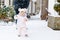 Adorable little baby girl making first steps outdoors in winter through snow. Cute toddler learning walking. Father