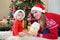 Adorable little baby and mother in santa hats playing celebrates Christmas, looking at camera. New Year`s holidays.