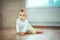 Adorable little baby sitting in bedroom on the floor with bottle with milk or water and laughing. Infant Childhood Kids People