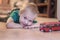Adorable little boy with blue eyes lays on the ceramic floor with toy red bus. Blonde hair, green t-shirt.