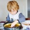 Adorable little boy helping and baking plum pie